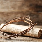 Crown of thorns and scroll on old wooden background